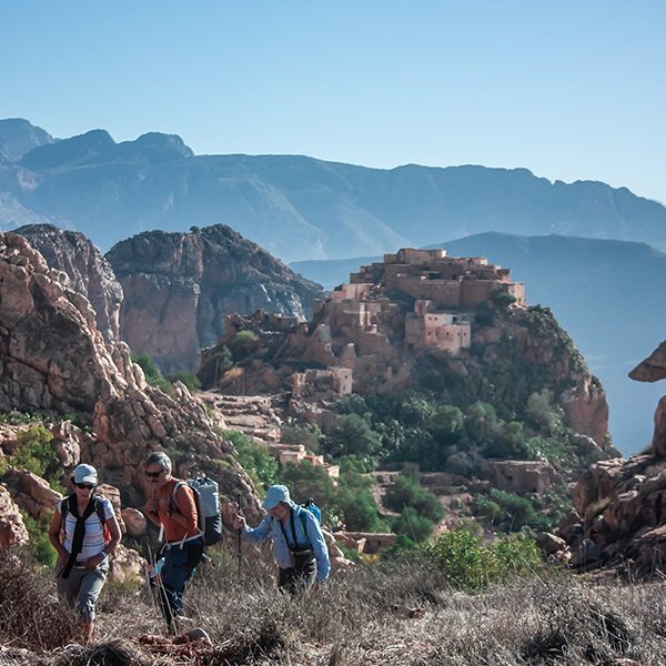 Hikers crossing the old village of Timjicht towards the summit Adad Madni